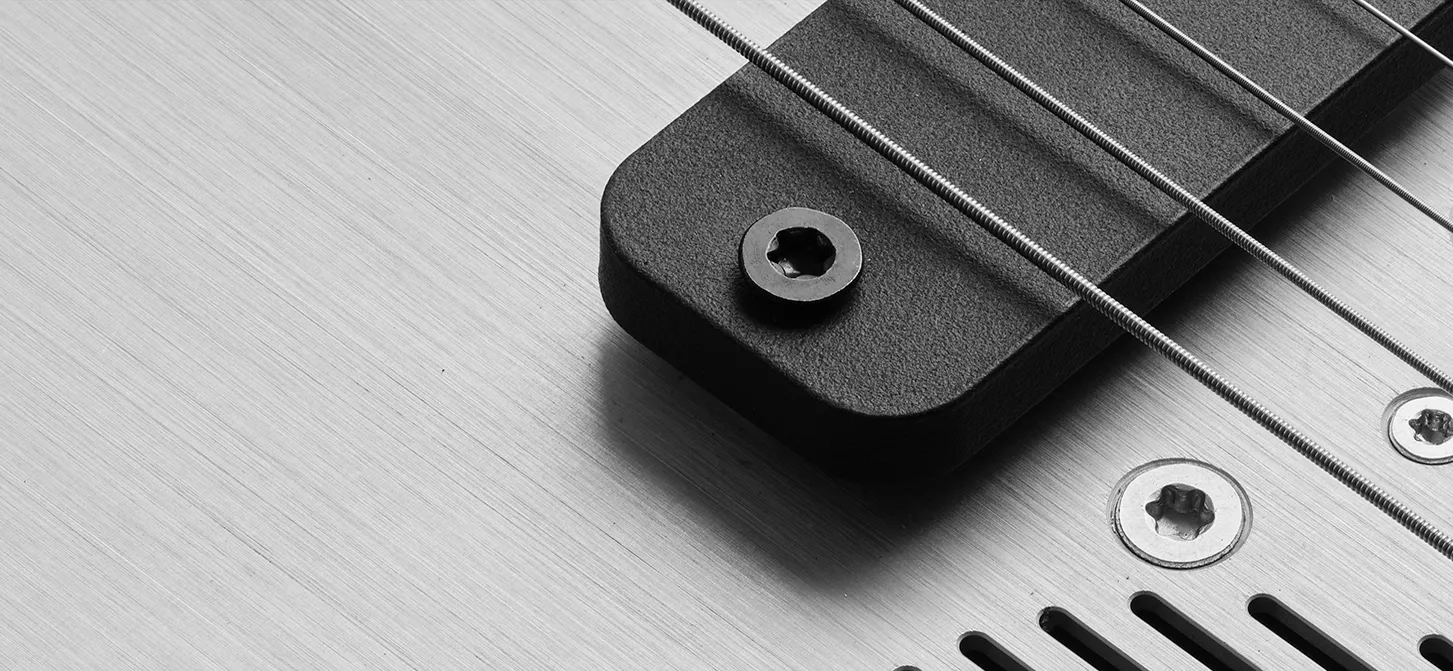 Close-up of the Mekani WAO pickup and steel strings over its brushed aluminum face